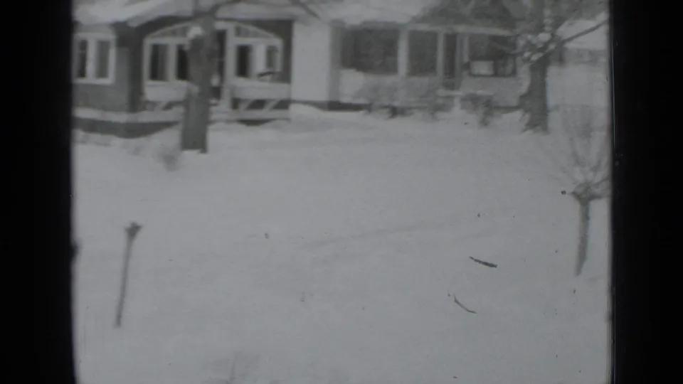 A snow-covered New York residential scene appears beyond a dark vertical window divider in 1939 8mm footage.