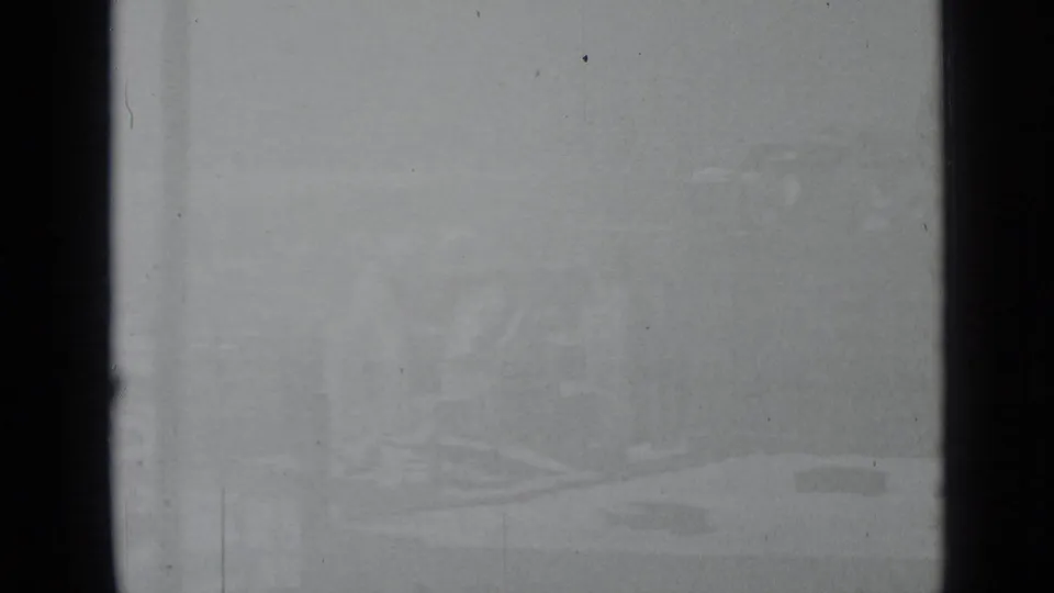Faded final 1939 New York frame with pale snow, faint outlines of a church structure, rooftops, and surrounding buildings through the window.