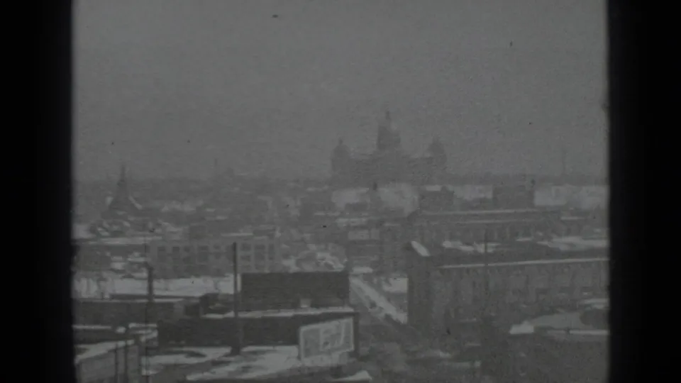 Elevated 1939 New York winter skyline with a distant domed landmark, snowy roofs, utility poles, and a dark window divider.