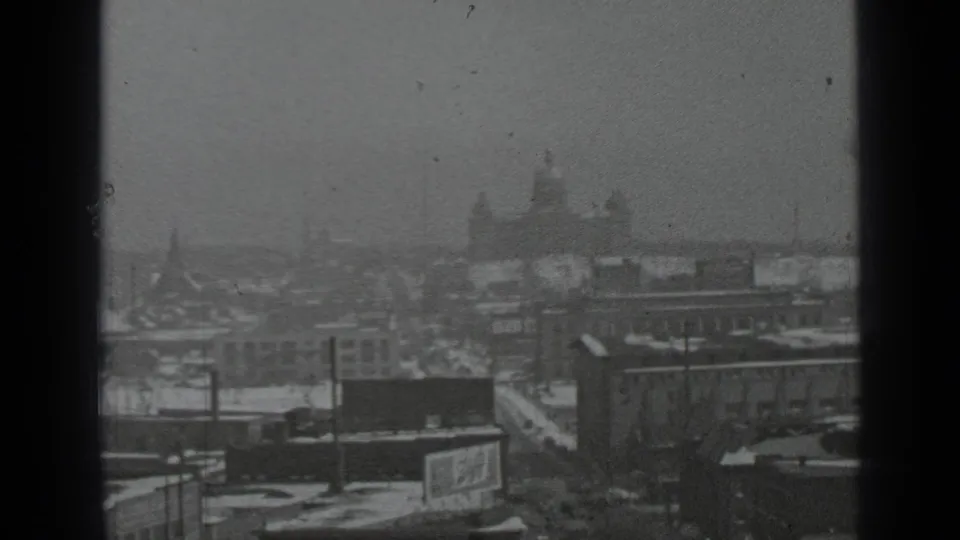 1939 New York snowy cityscape with distant domes, flat roofs, street corridors, and a dark window frame in the foreground.