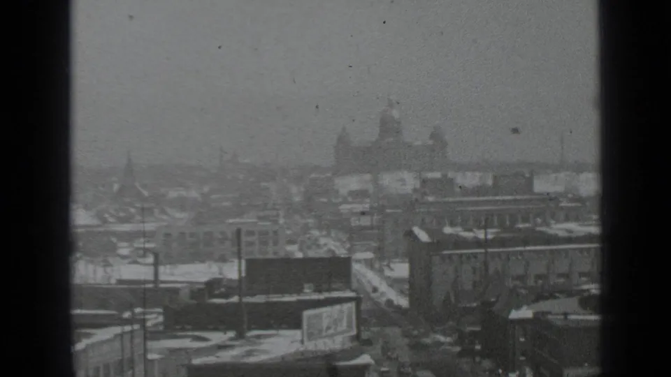 1939 New York home-movie frame showing a hazy snowy skyline from above, with a distant domed building and streets below.