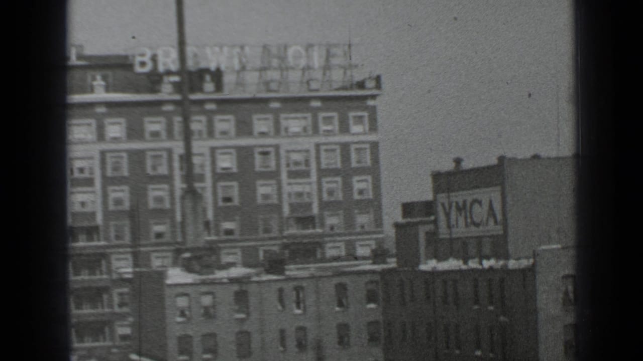 Brown Hotel building and nearby YMCA sign seen across snowy rooftops.