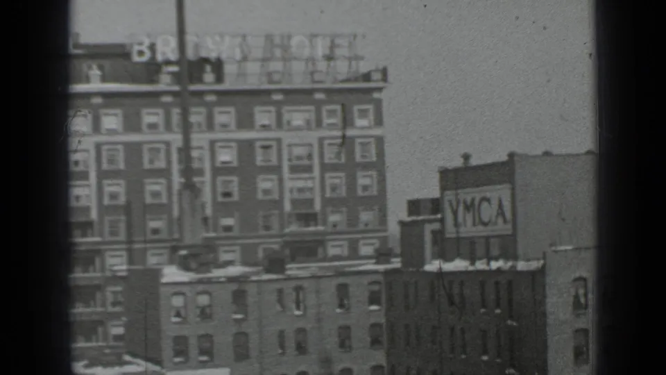 1939 New York frame showing the Brown Hotel and YMCA signage from an elevated viewpoint, with grain, scratches, and dark 8mm borders visible.