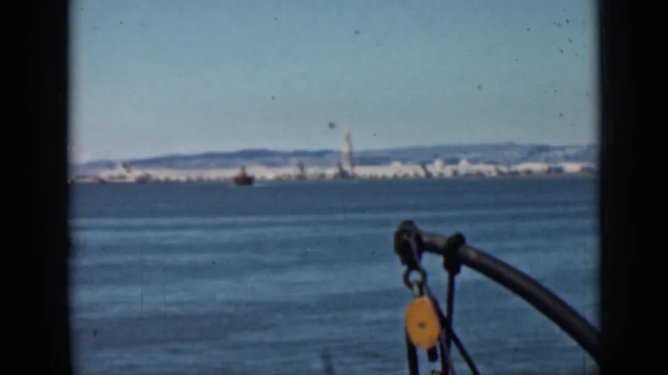 Boat-level 1939 San Francisco Bay view with the distant waterfront skyline and foreground pulley hardware visible through the 8mm frame.