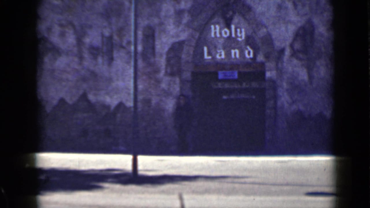 Dark entrance marked Holy Land with a shadowed figure near the doorway.