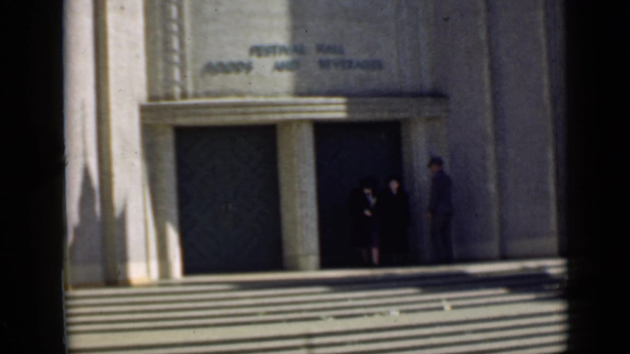 People standing at the entrance of a large building with broad steps.
