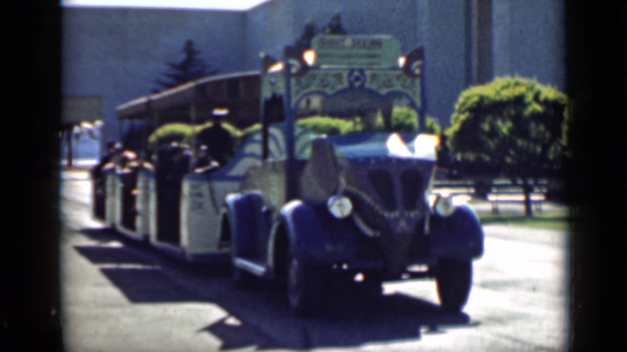 Blue-and-cream open tour tram with passengers on a sunny city street.