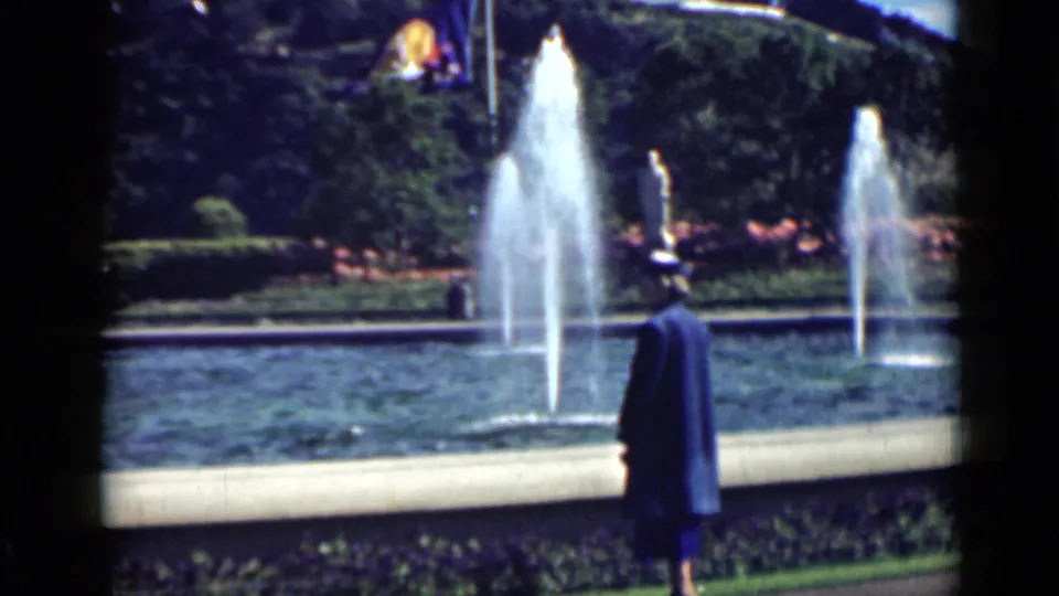 Late-1930s 8mm footage shows a woman in blue watching tall fountain jets in a landscaped San Francisco park.
