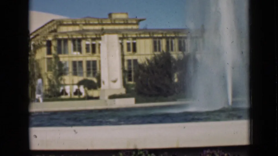 The final frame holds on fountain water and the classical building, with dark film-frame borders and soft focus visible.