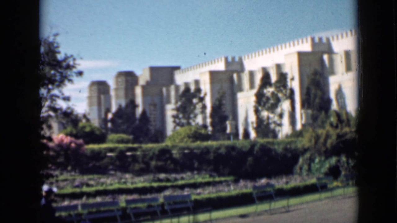 White castle-like building above landscaped greens and trees.