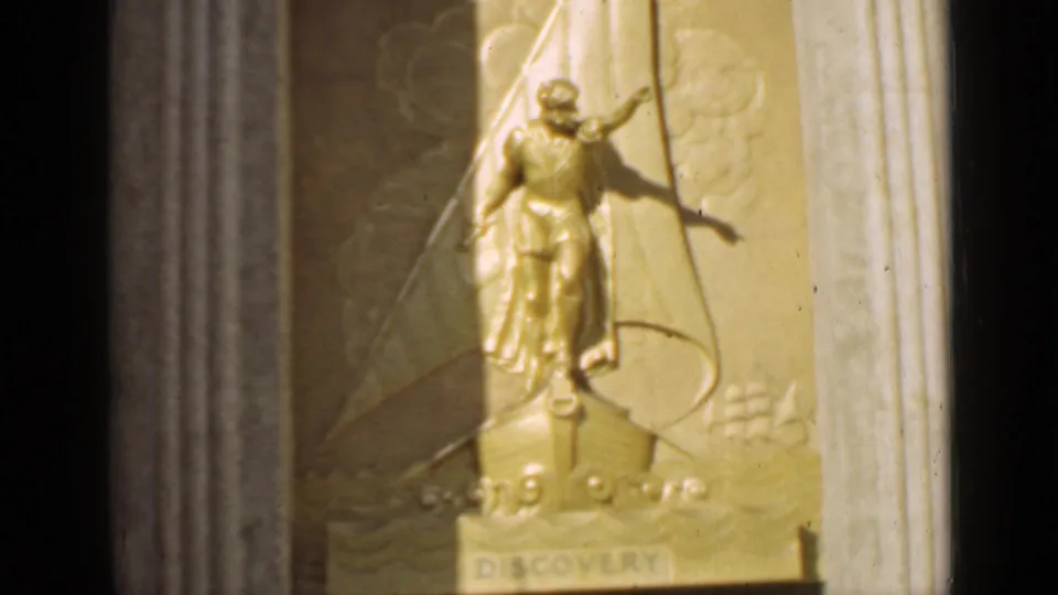 Close view of a golden DISCOVERY relief sculpture in 1939 San Francisco footage, with a figure, sail form, and architectural border visible.