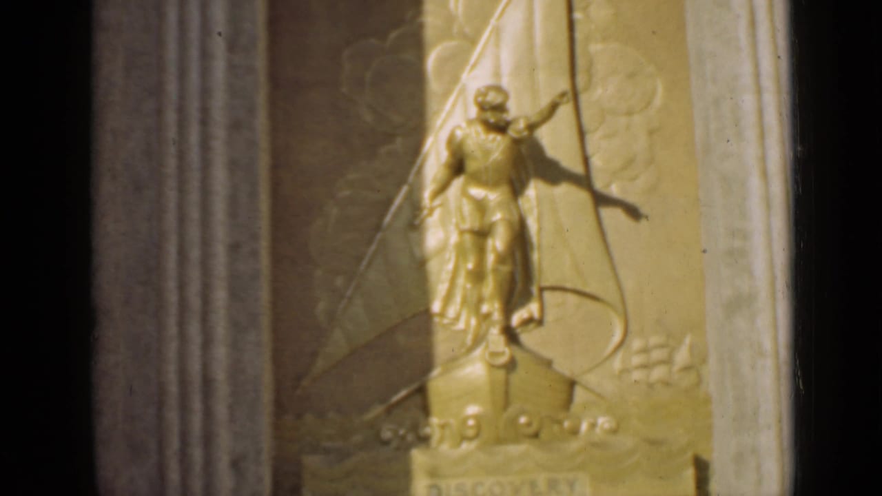 Soft close-up of the same gold relief figure and ship motif beside a column.