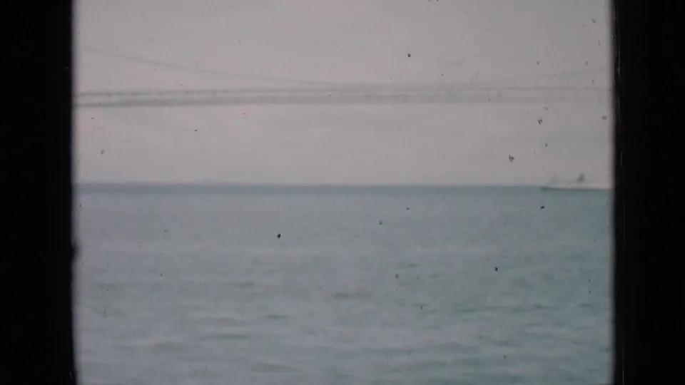 1939 San Francisco 8mm frame with a pale bay view, distant bridge line, and small sailboat on the water.