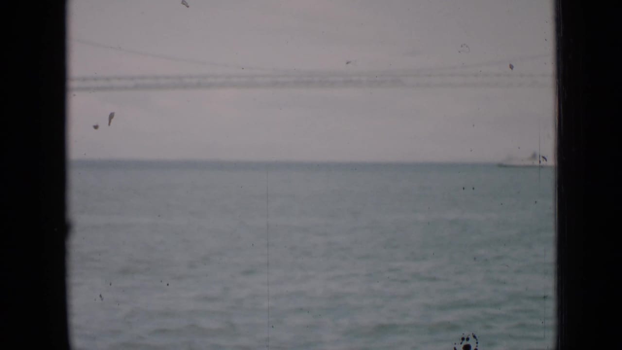 Open water with a distant white ship near the horizon, framed by dark vertical edges.