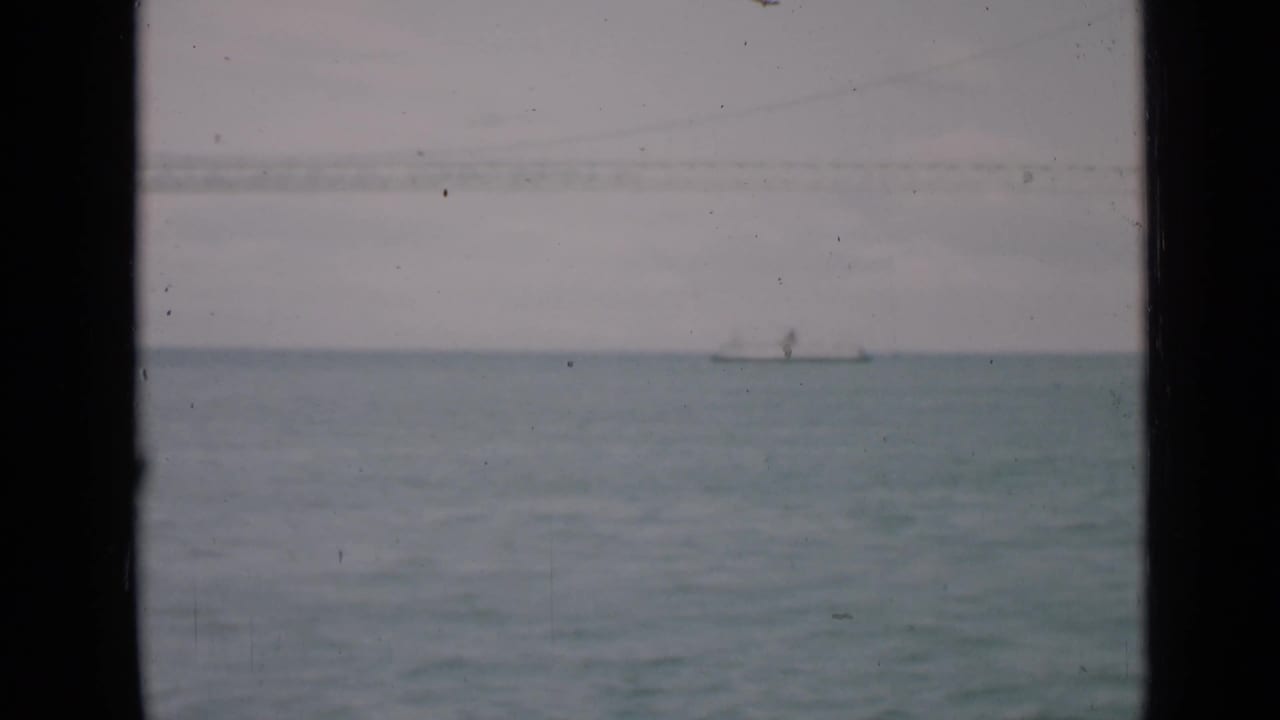 Small sailboat on the horizon over calm water, framed by window edges.