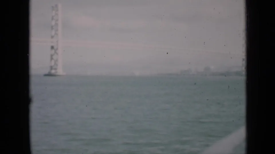 1939 San Francisco bay view with a distant bridge tower, soft skyline, and dark window-like framing.