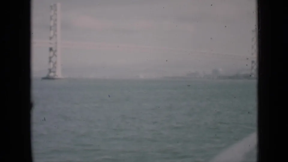 Steady 8mm view of bay water and a likely San Francisco bridge tower seen through dark framing.