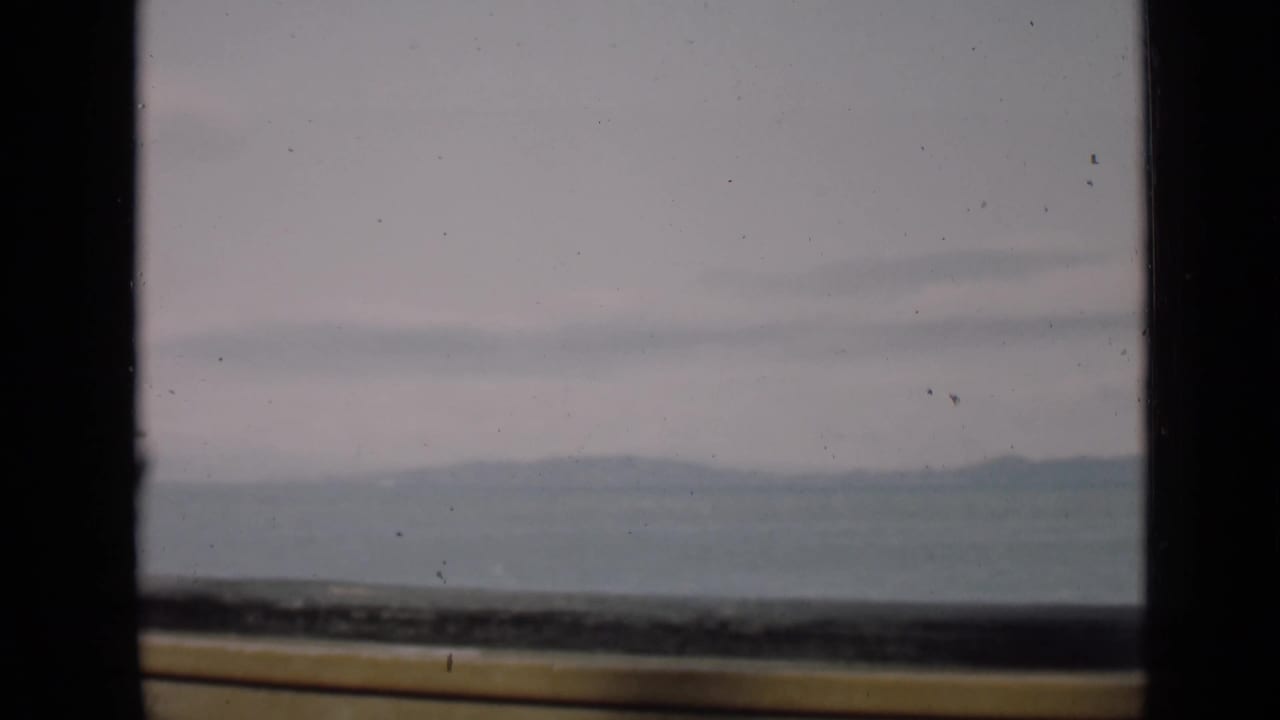 Hazy distant ridges seen through dark window framing with a yellow ledge below.