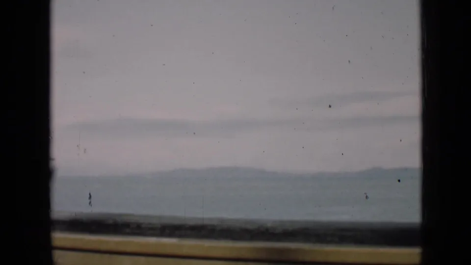 1939 San Francisco 8mm still with a hazy horizon, distant ridges, dark window border, and yellow ledge at the bottom.