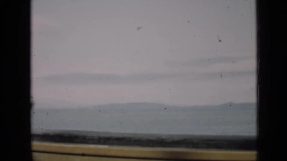 A San Francisco 1939 home-movie frame showing distant hills or mountains softened by haze through dark window borders.