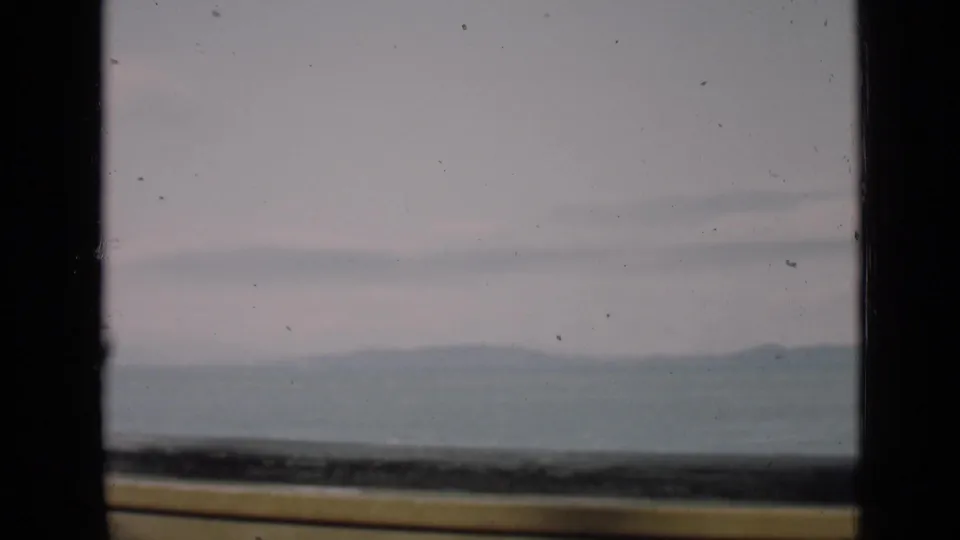 1939 8mm San Francisco boat-deck view showing a railing, bay water, distant hills, and overcast sky.
