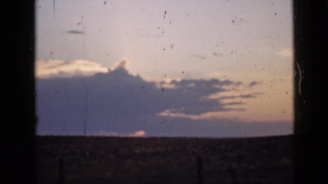 A Utah home-movie sunset frame from 1939 shows purple clouds and pale pink sky above a low, empty horizon, with dust and scratches visible.