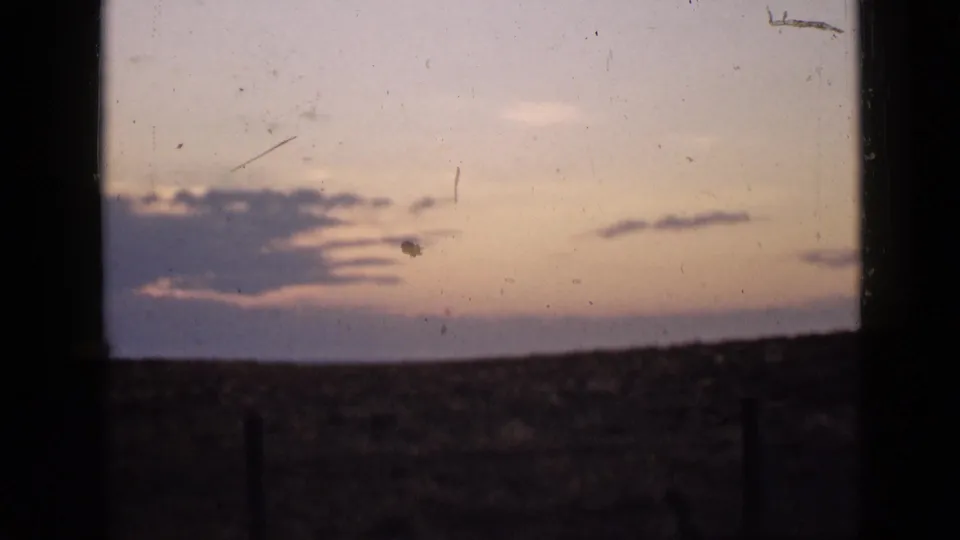 1939 Utah 8mm footage shows layered evening clouds over open plains, with a dark window-like border and noticeable film dust.