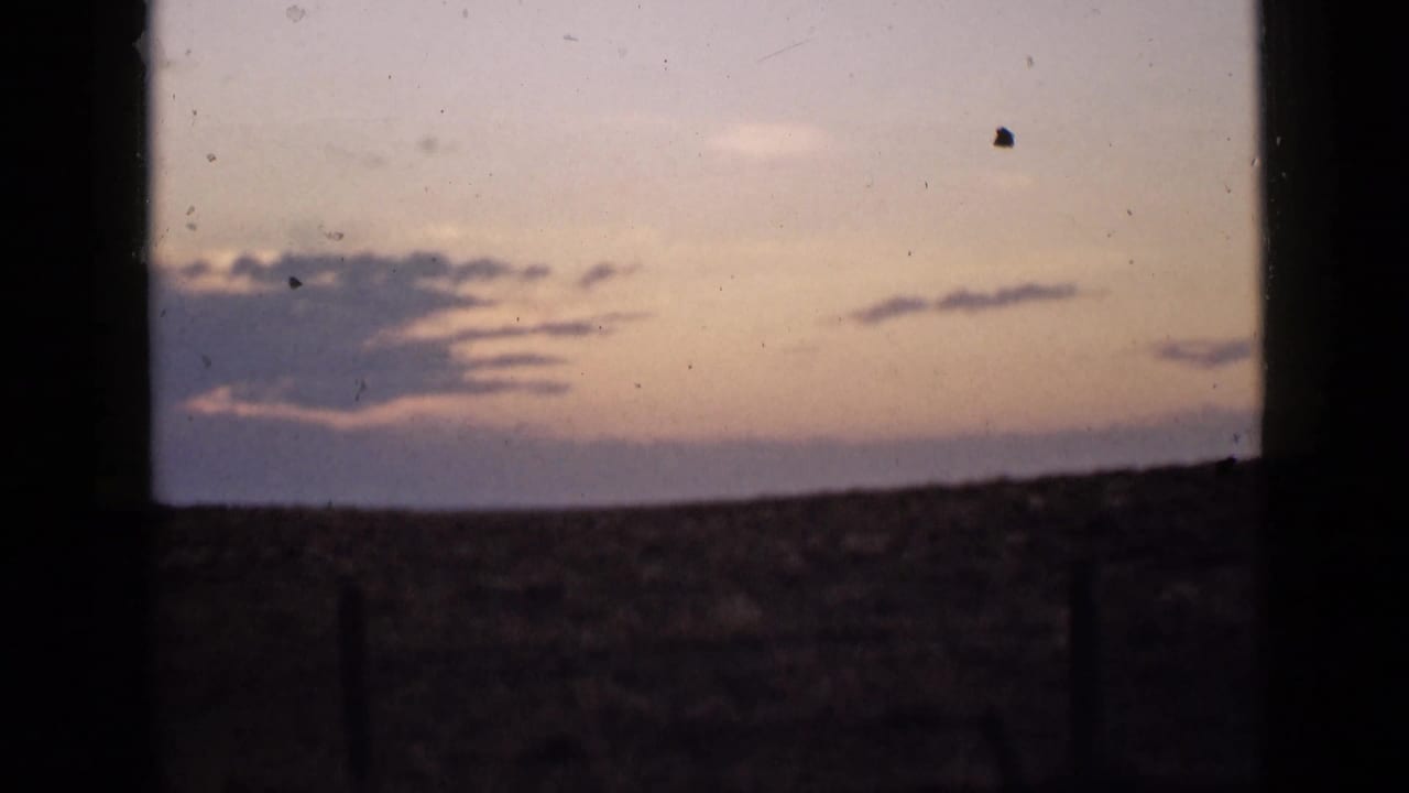 1939 Utah landscape frame showing an open horizon and lavender cloud band at dusk, viewed through dark vertical borders.
