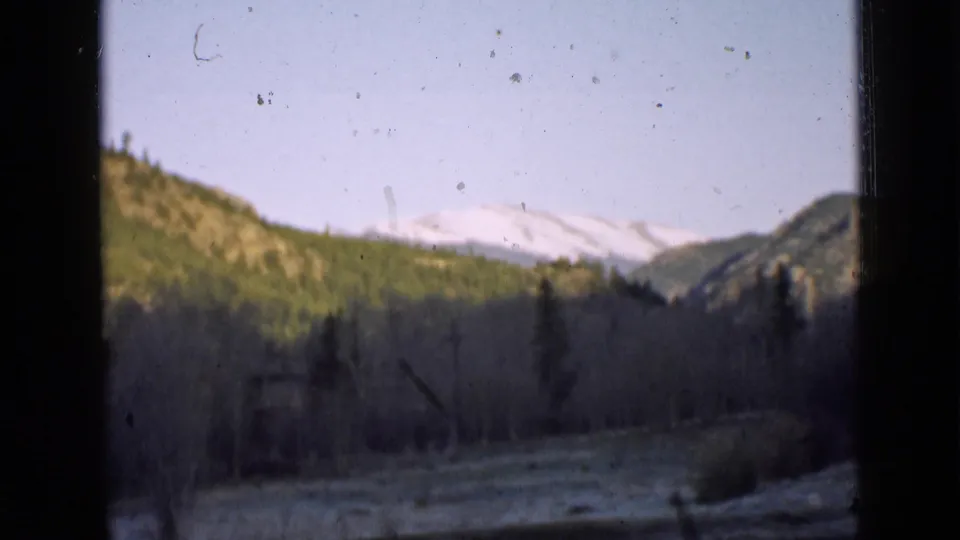 A 1939 Utah mountain landscape appears in a home-movie frame, with snowy peaks, pine slopes, and visible film dust.