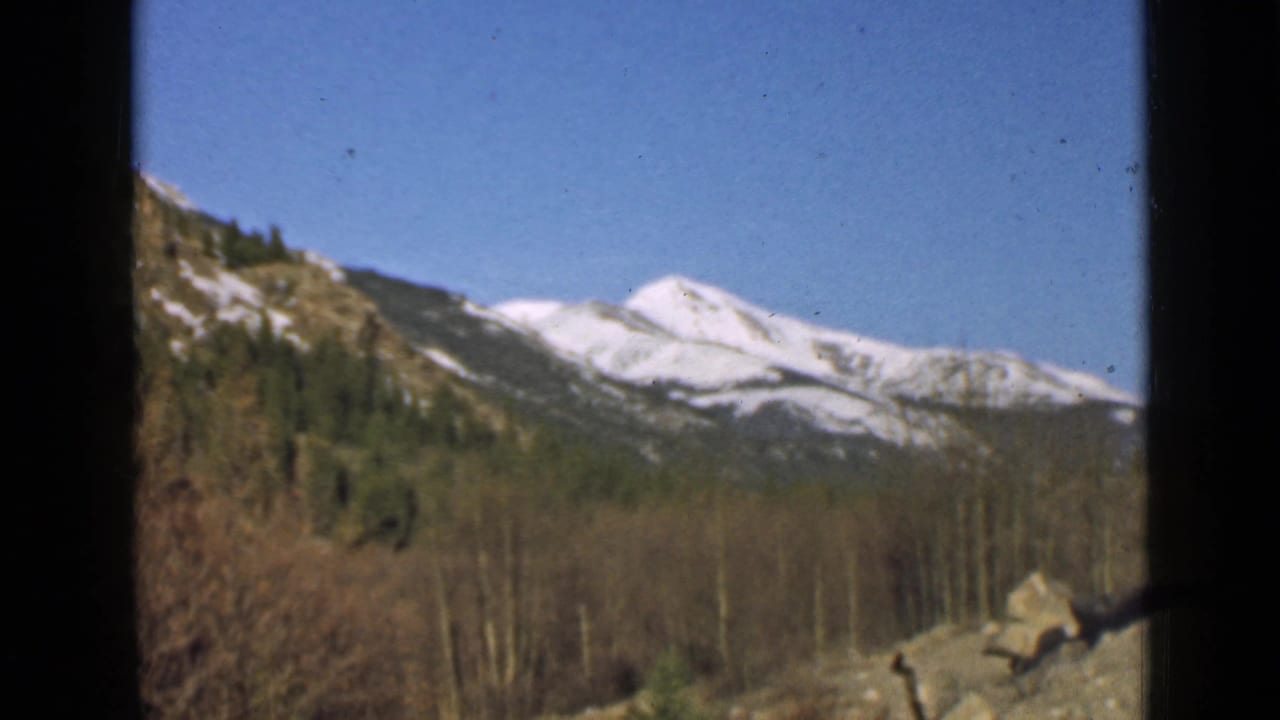 Mountain landscape with snow-covered peaks and a dark vertical window edge.