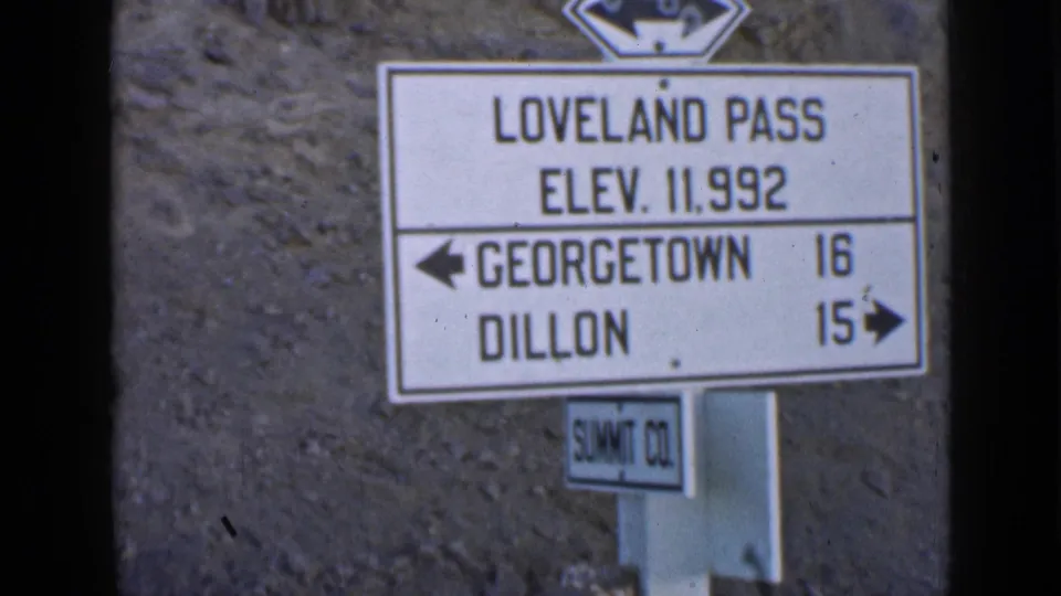 Close view of a Loveland Pass sign showing elevation 11,992 feet and directions toward Georgetown and Dillon.