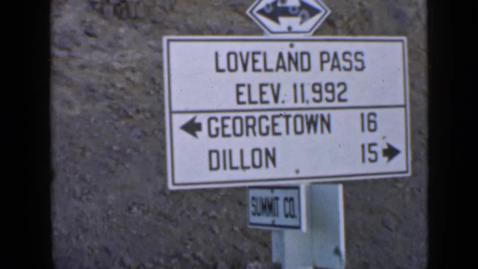 1930s 8mm frame showing the Loveland Pass elevation sign and directional distances to Georgetown and Dillon.