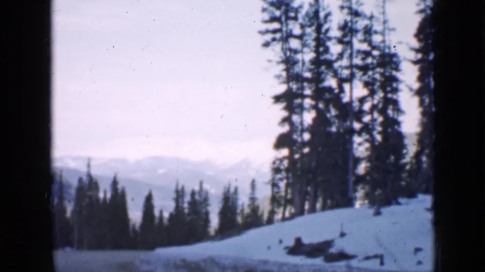 A Utah mountain landscape shows snow, dark evergreens, and distant ridges in vintage 8mm color.