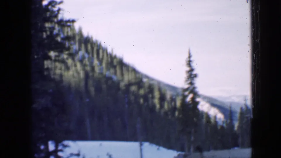 1939 Utah 8mm view of a snowy evergreen slope, with soft-focus distant ridges and dark film or window borders.