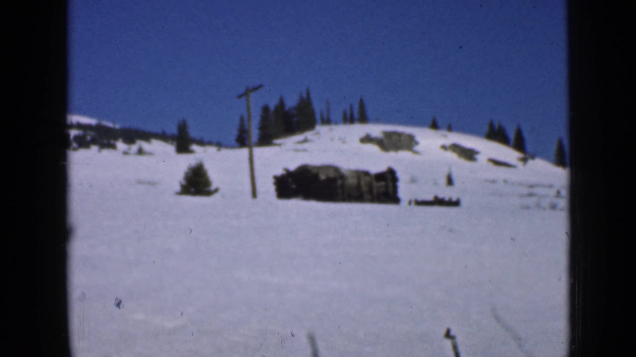 1939 Utah mountain snow scene with a utility pole, dark evergreens and a partially snowbound rustic structure.