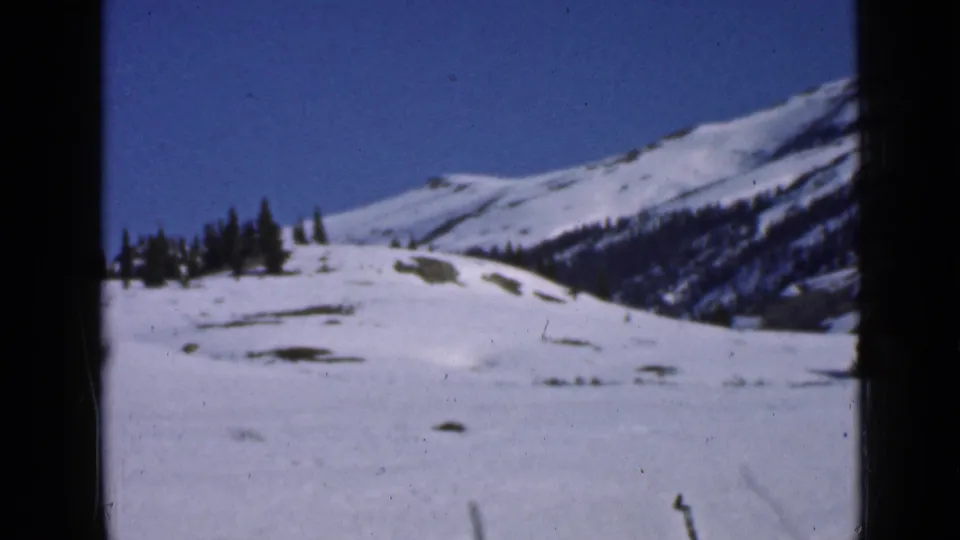 1939 Utah 8mm view across snowfields toward evergreen trees and mountain ridges beneath a clear blue sky.