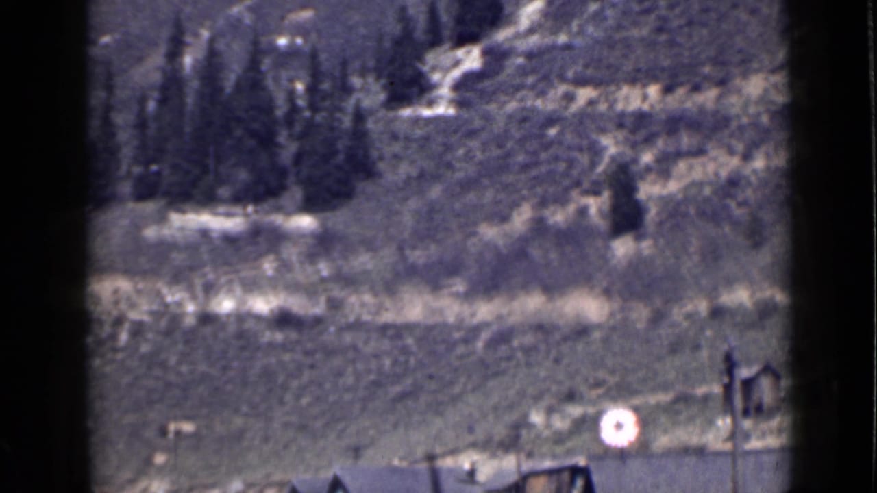 1939 Utah frame showing mostly open hillside, rough terrain, a partial building edge, and a bright circular lens flare or reflection.