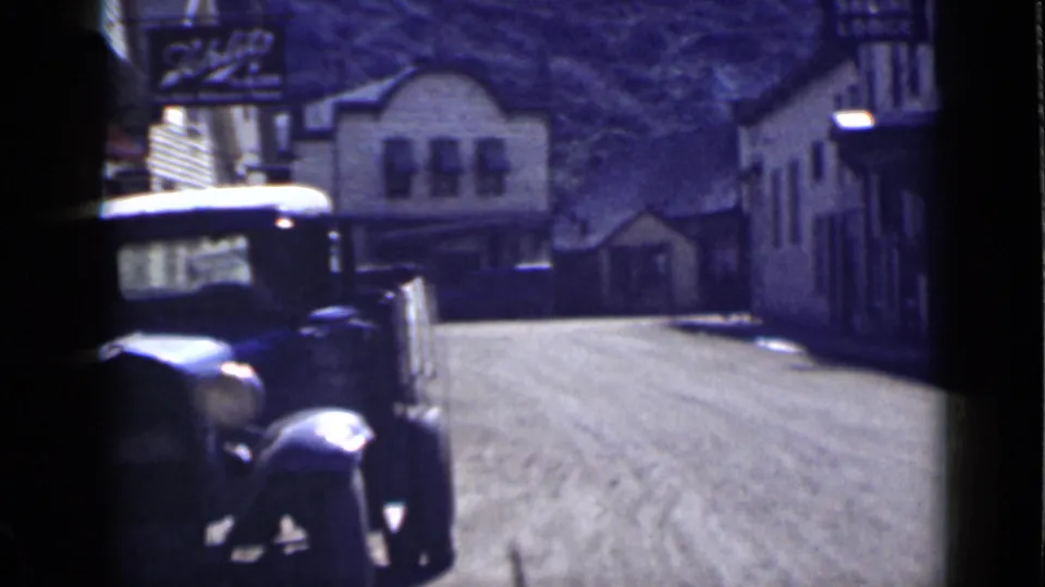 A 1939 Utah street view with an older automobile in the foreground, low buildings, dirt road surface, and Shrine Lodge signage.