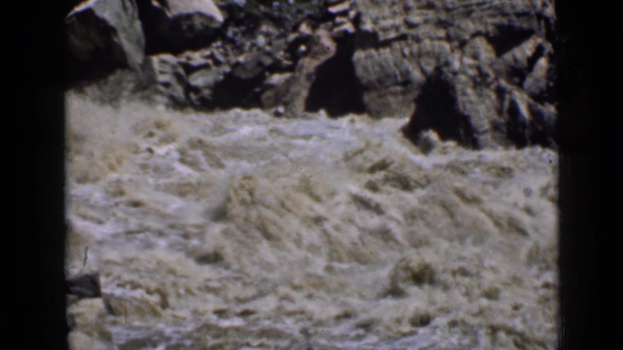 1939 Utah 8mm frame showing turbulent muddy river water moving through a rocky canyon.
