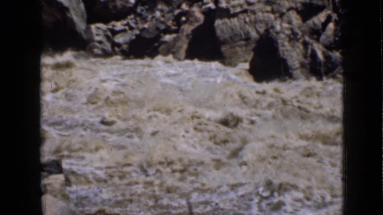 1939 Utah home-movie frame of a muddy river surging through rocks in a rugged canyon.