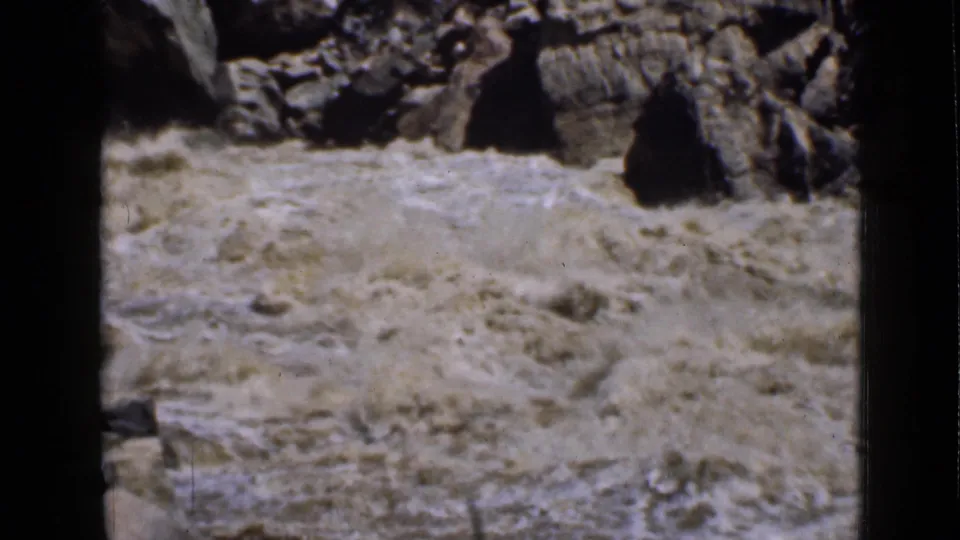 1939 Utah home-movie frame of a muddy river surging through rocks in a rugged canyon.