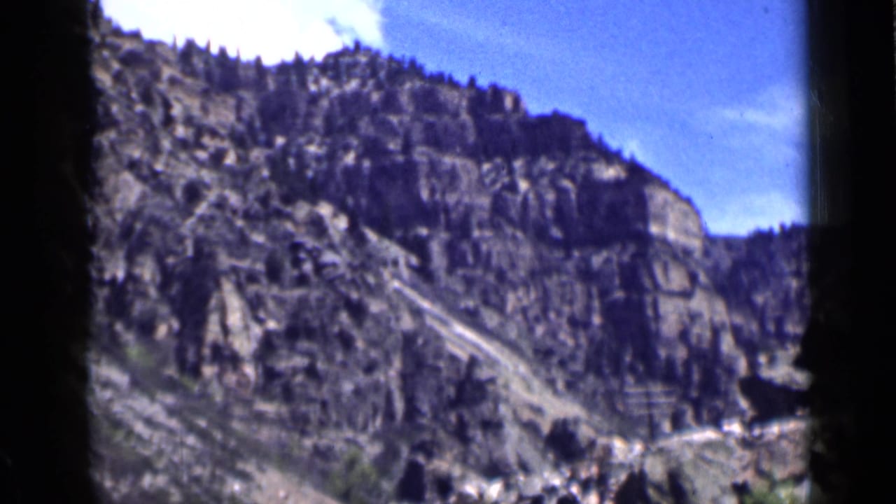 1939 Utah home-movie frame of a rocky canyon slope and sparse vegetation beneath blue sky.