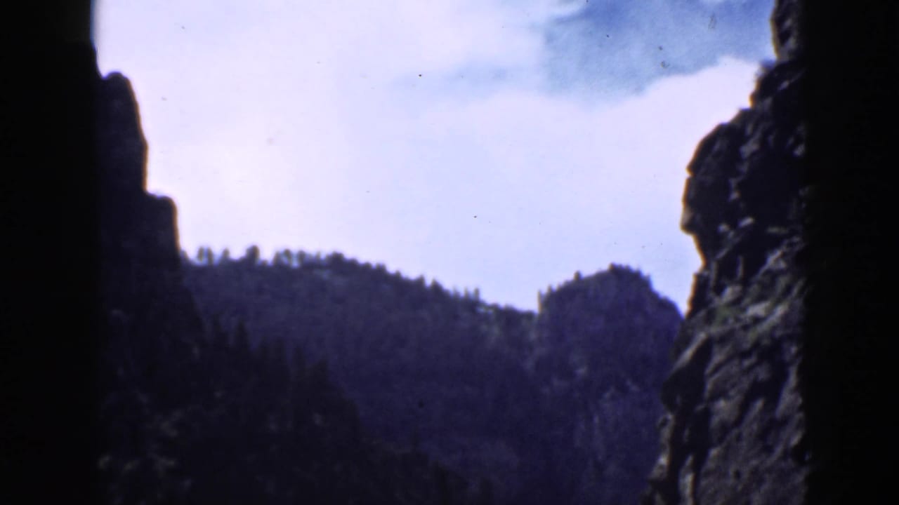 1939 Utah 8mm frame showing a canyon ridge between dark rock walls, with trees along the horizon.