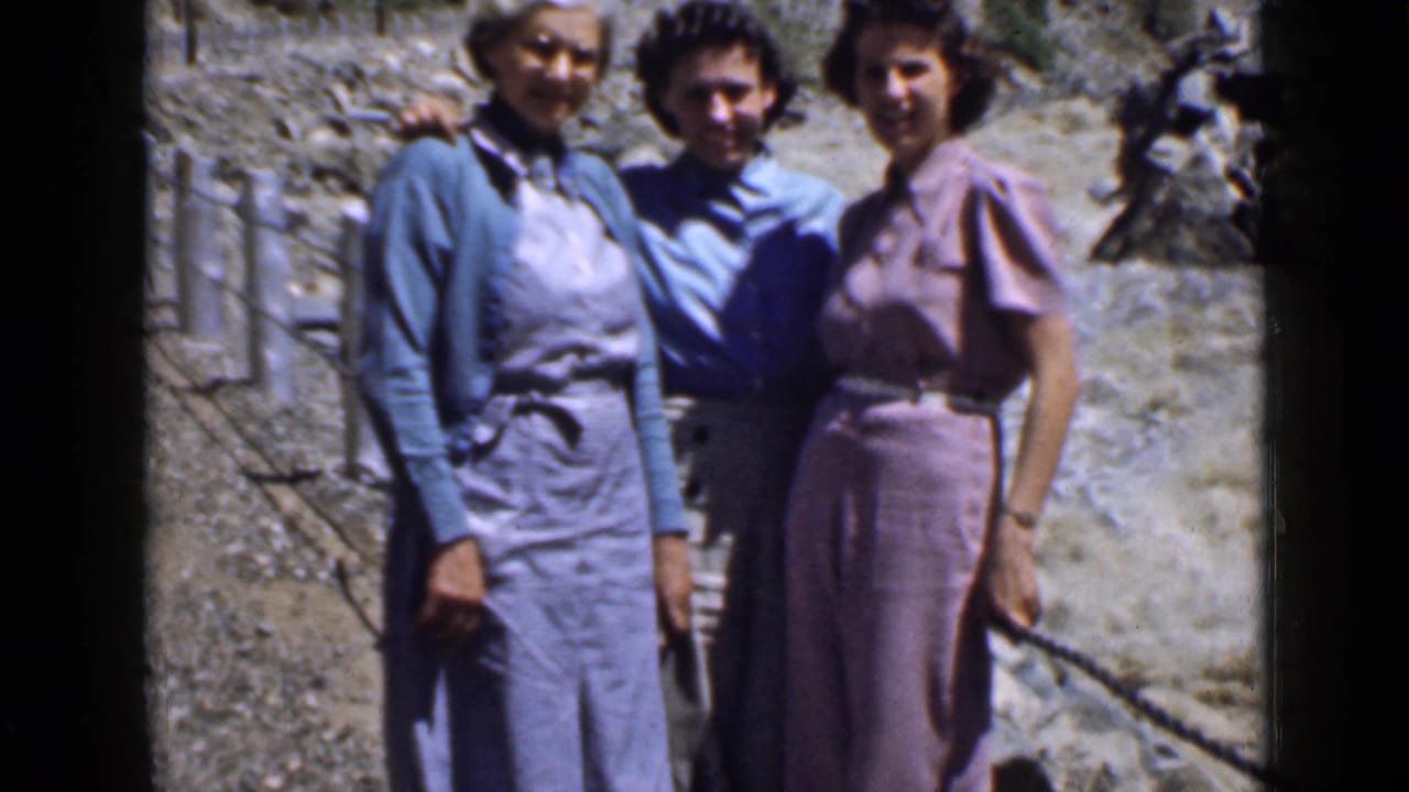 Three women in 1930s-style clothing pose arm in arm on a rocky Utah trail during a home-movie excursion.