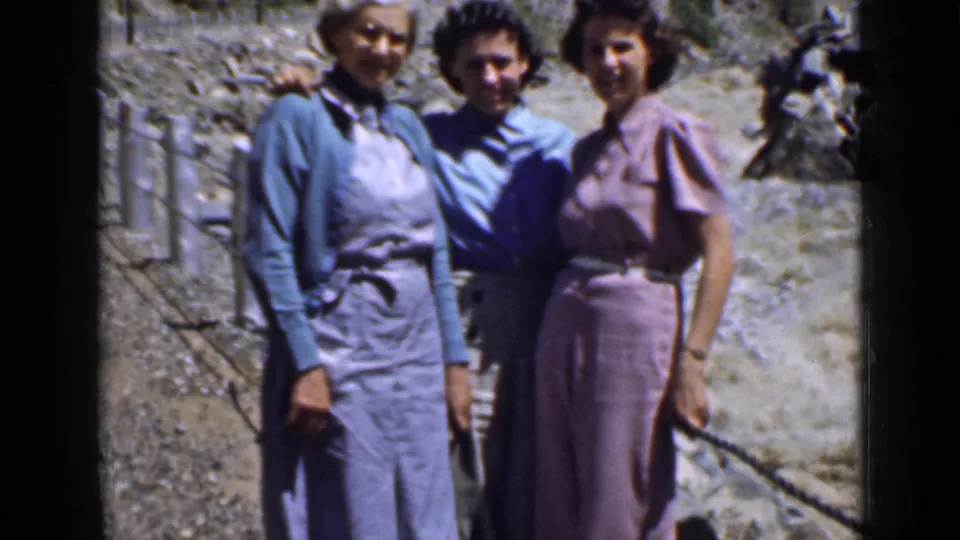 Three women in 1930s-style clothing pose arm in arm on a rocky Utah trail during a home-movie excursion.