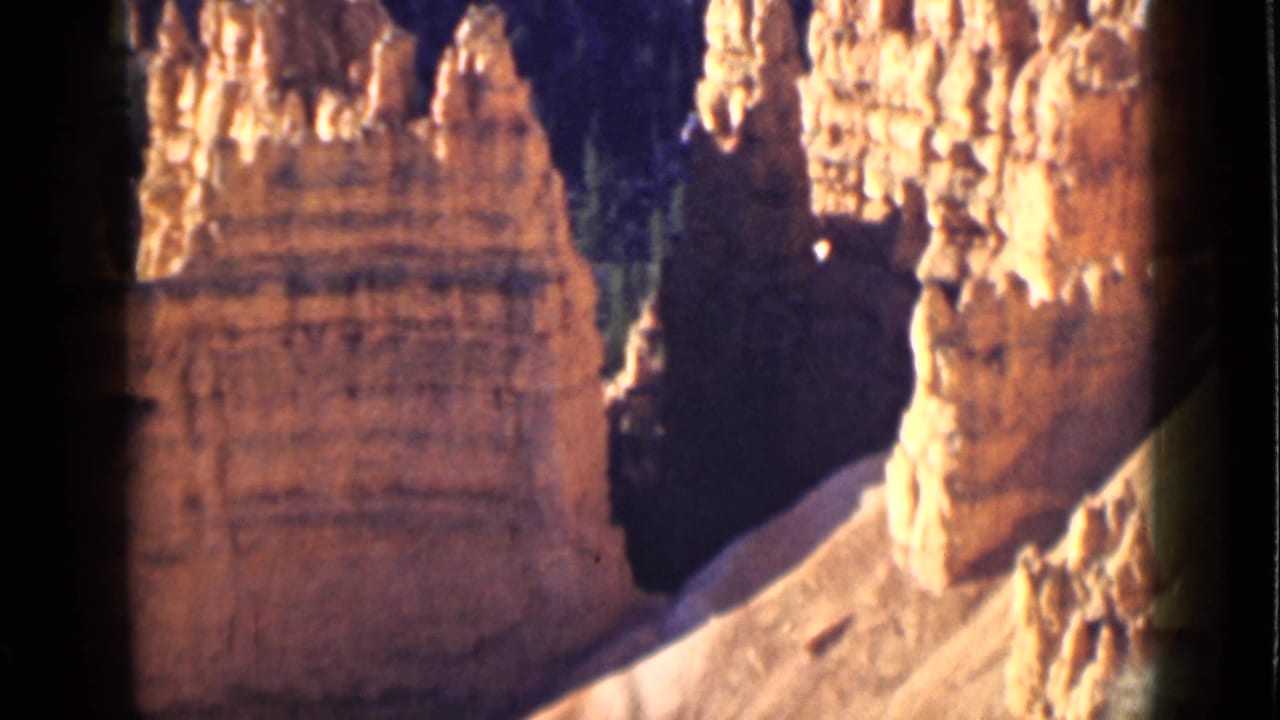 1939 Utah 8mm frame showing tall Bryce Canyon rock towers, bright sunlit caps, and a deep shadowed passage between formations.