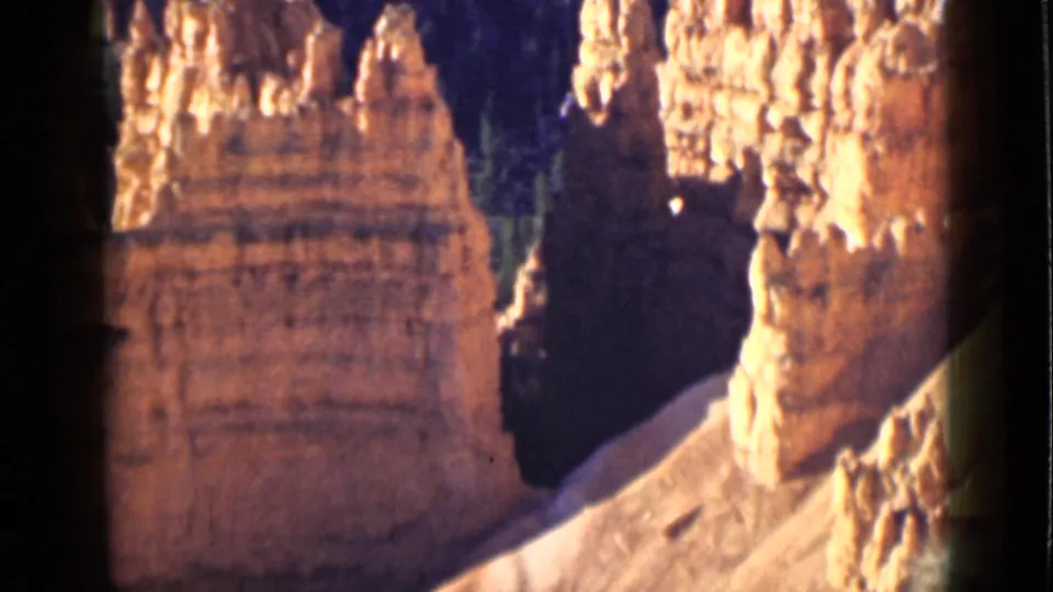 1939 Utah 8mm frame showing tall Bryce Canyon rock towers, bright sunlit caps, and a deep shadowed passage between formations.