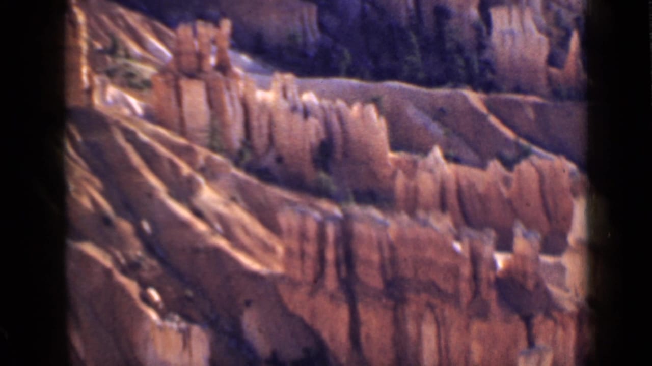 1939 Utah 8mm frame looking across Bryce Canyon’s layered cliffs, pale eroded ridges, and scattered evergreen trees.