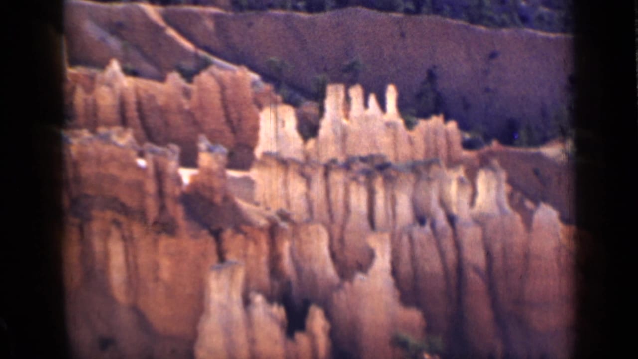 1939 Utah 8mm frame with cream hoodoo formations and vertical erosion lines across the canyon face.