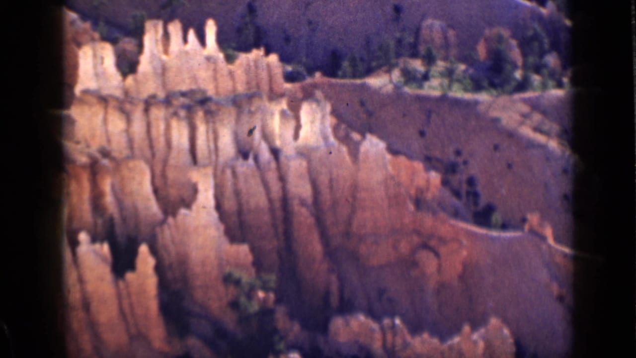 Final 1939 Utah home-movie frame showing hoodoo clusters, dry red slopes, and sparse vegetation in the canyon.